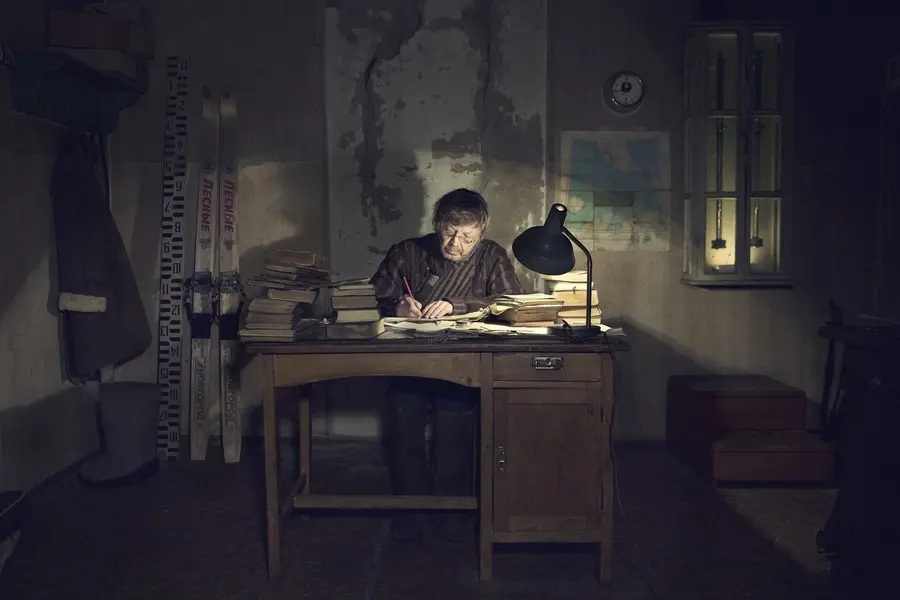 A man sits at a desk in a dark room.