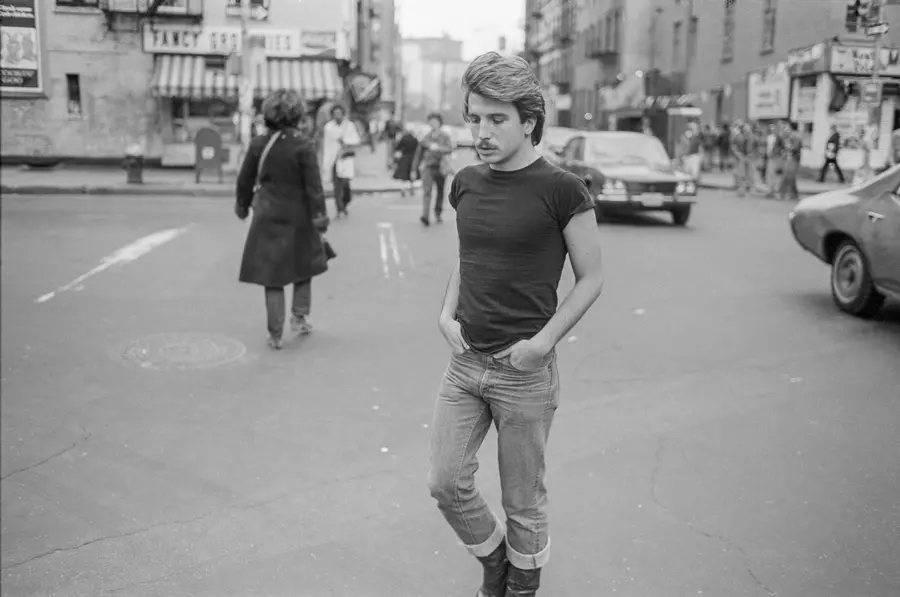 A man walks toward the camera crossing a busy city street. 