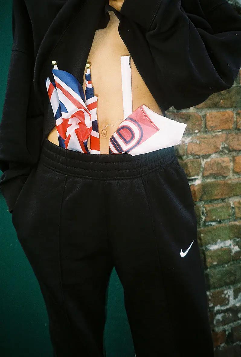 Photograph of a person with flags tucked into the waistband of their sweatpants