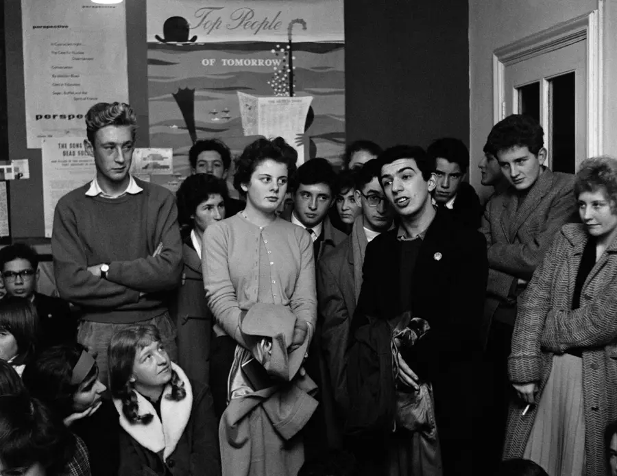 Black & White photograph by Roger Mayne of a group of people standing at The Partisan Coffee House, displayed at The Photographers' Gallery in London