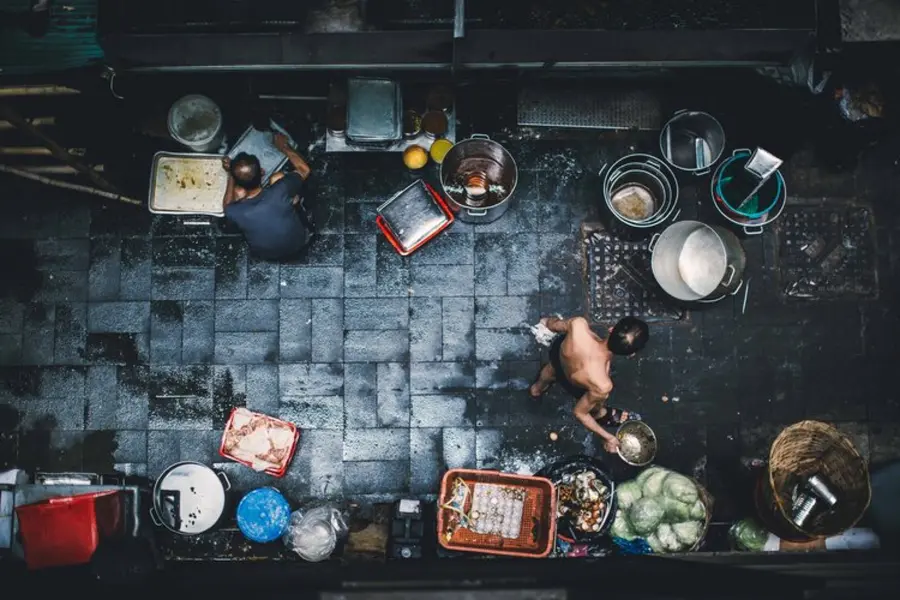 Birds-eye view of an Asian street scene with people and pots and pans in it