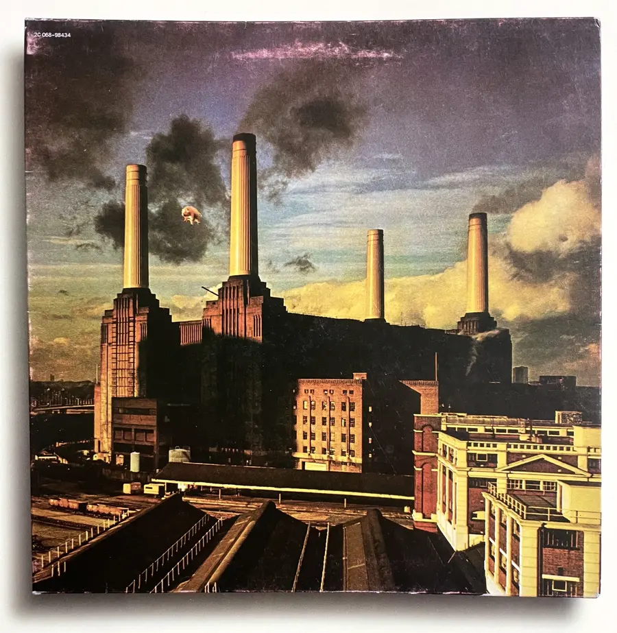 The cover of Pink Floyd's album 'Animals' featuring a colour photo of Battersea Power Station with a large, pink inflatable pig suspended between the front two of its four, protruding, white chimneys.