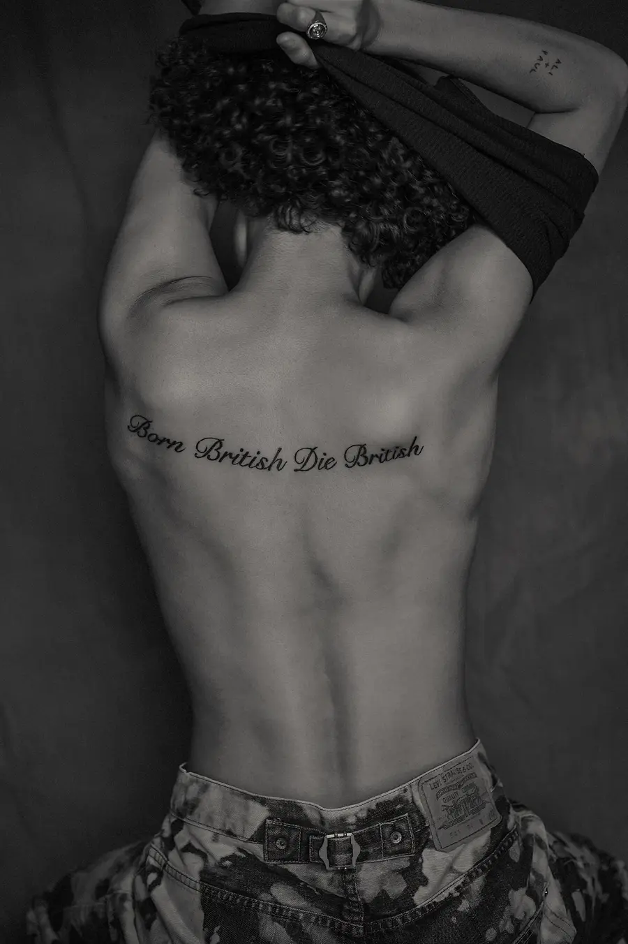 black and white image of rene matic's back with the words 'born british, die britis' tattooed across it