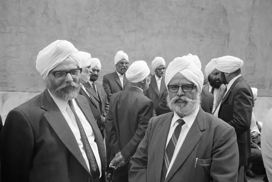 Black and white image of a group of elder men dressed in suits and turbans gathered together for a wedding.