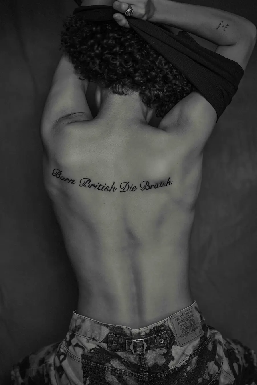 black and white image of rene matic's back with the words 'born british, die britis' tattooed across it