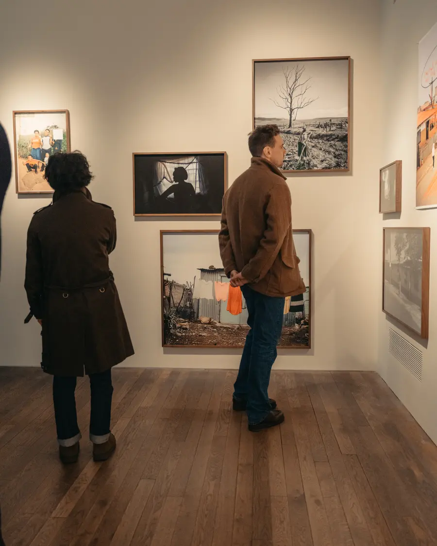 Colour image of two people looking at photographic prints displayed on a gallery wall.