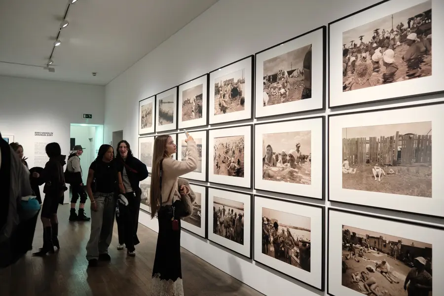 People looking at a series of framed vintage photos on an exhibition wall.