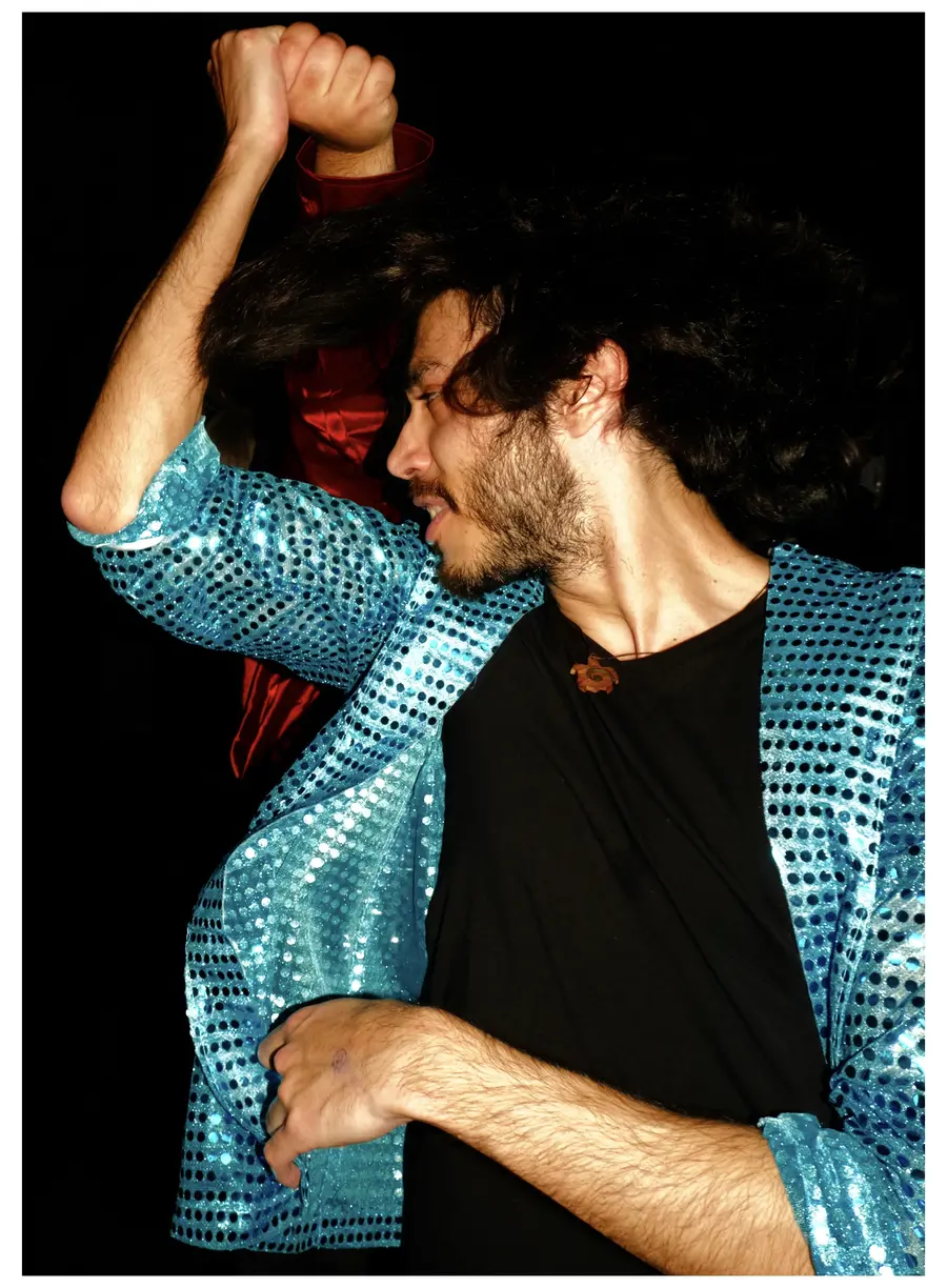Photograph of a person in a nightclub dancing whilst holding someones hand behind them.