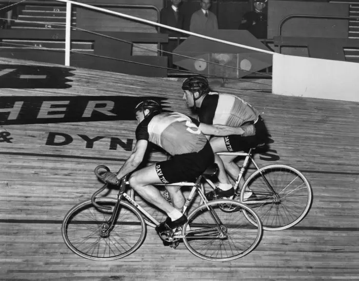 Black and white photo of cyclist Albert Bruylandt giving cyclist, Rene Andriaenssens, a push forward