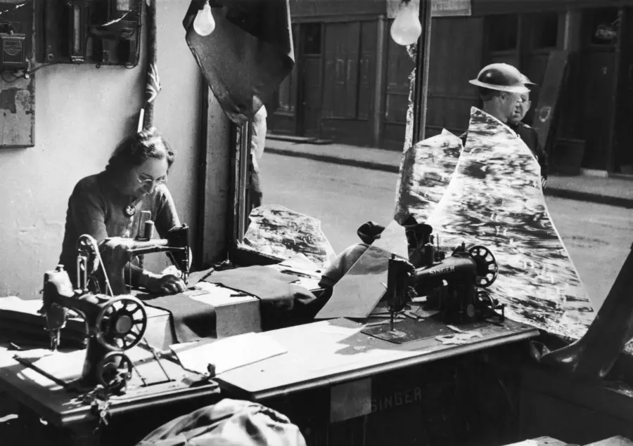  Black and white photograph of a woman working amongst the broken glass of a tailor’s shop.