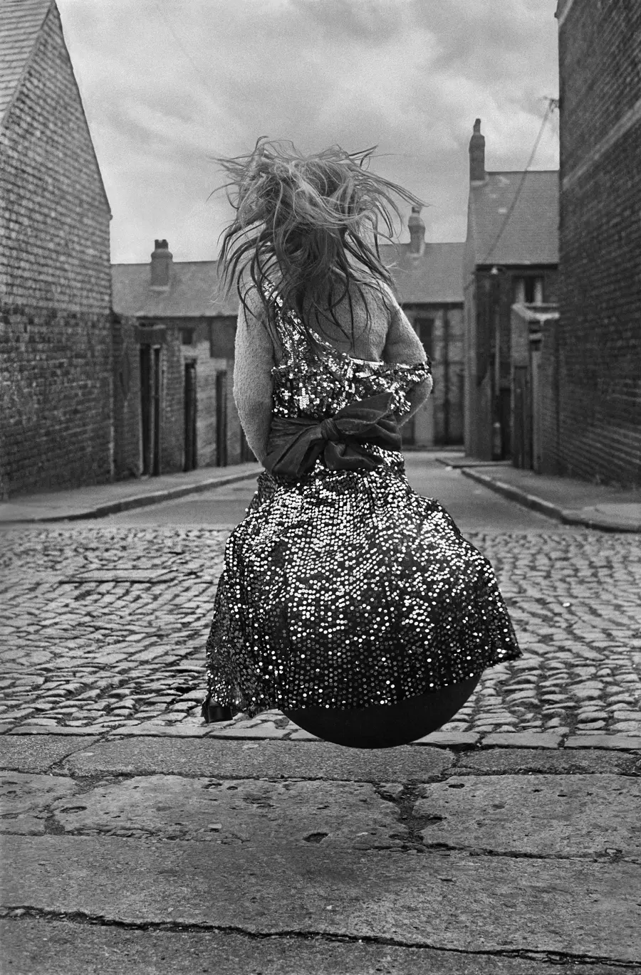 A young Girl on a Spacehopper in a cobbled street.