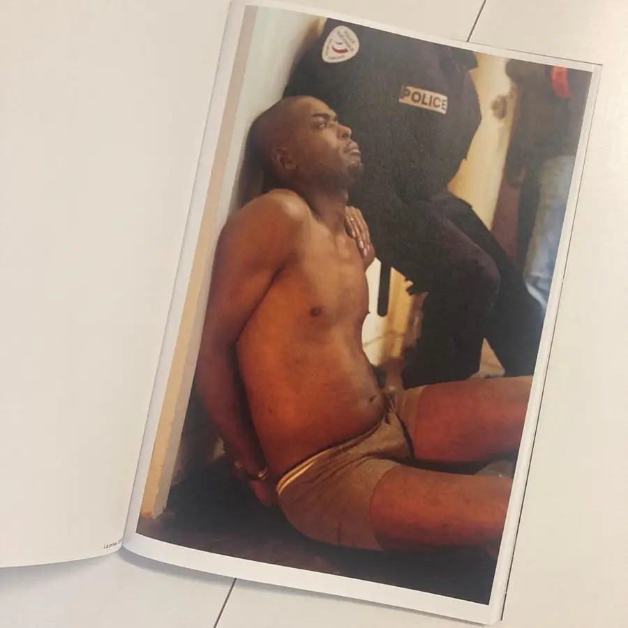 A book open on a page where a topless man crouches on the floor.