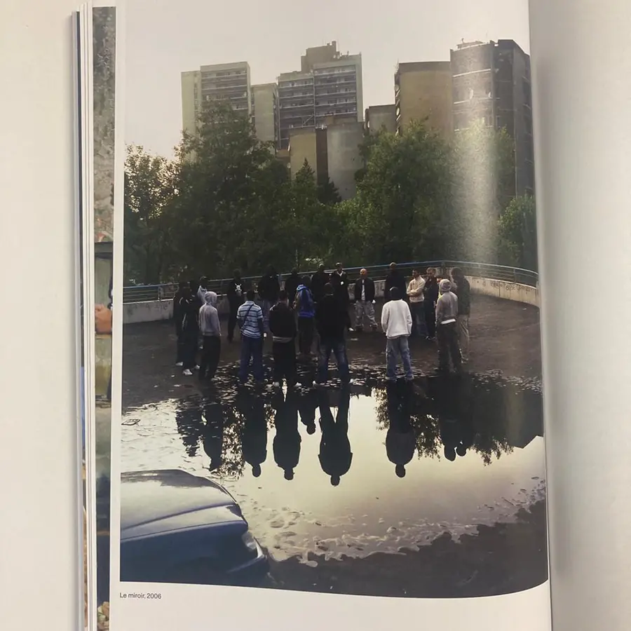 A book open on a page of a photograph of a group of people standing with flats in the background.