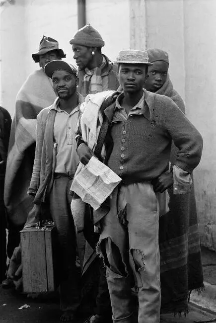 Black and white photograph of five young black men standing and staring off into the distance. One of them holds a document in his hand.
