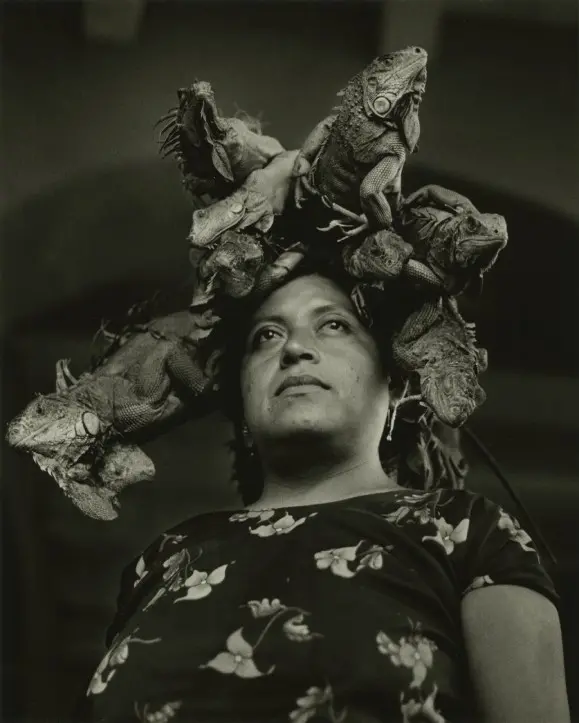 Black and white photograph of a woman with a crown of iguanas on top of her head