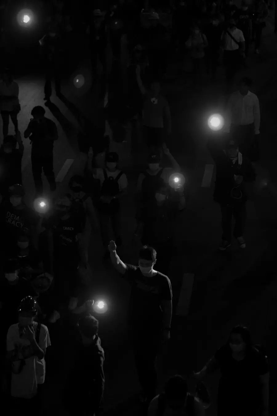 A photograph taken in the night with people holding one arm up and lights.