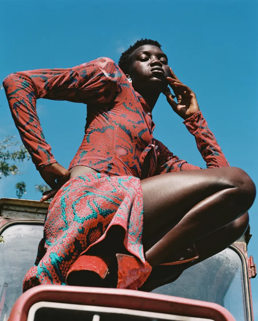 A person standing on a car with blue sky in the background.