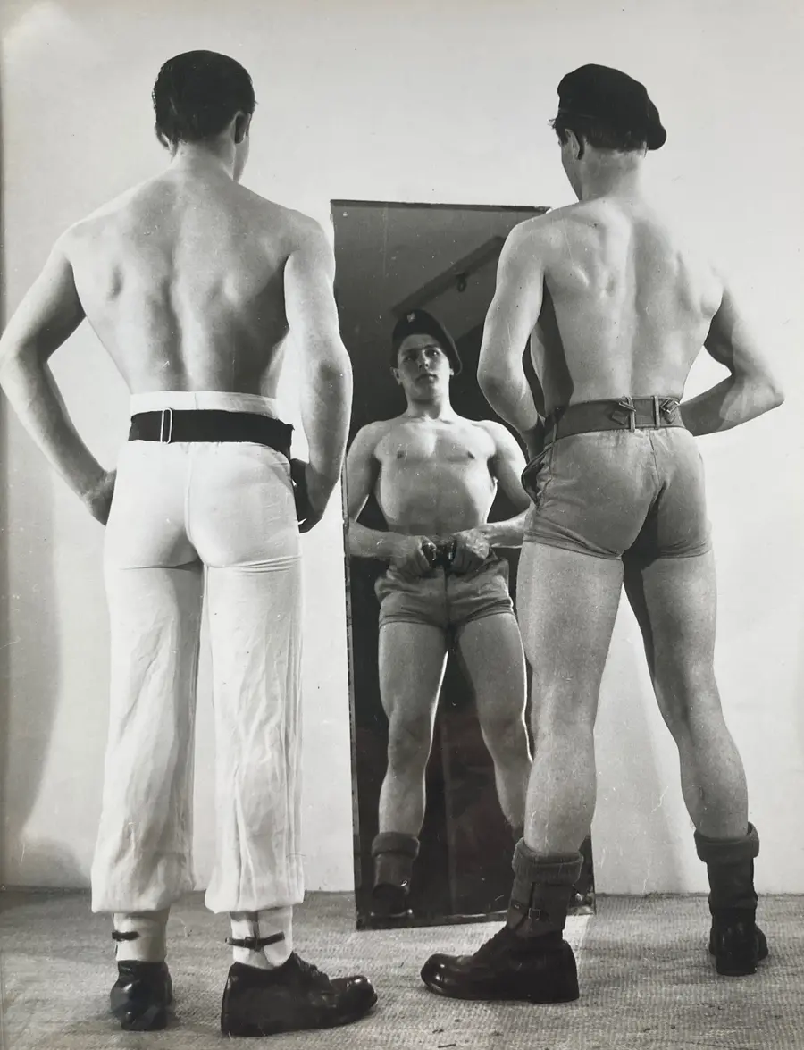 Two men with their backs turned to the camera face a mirror