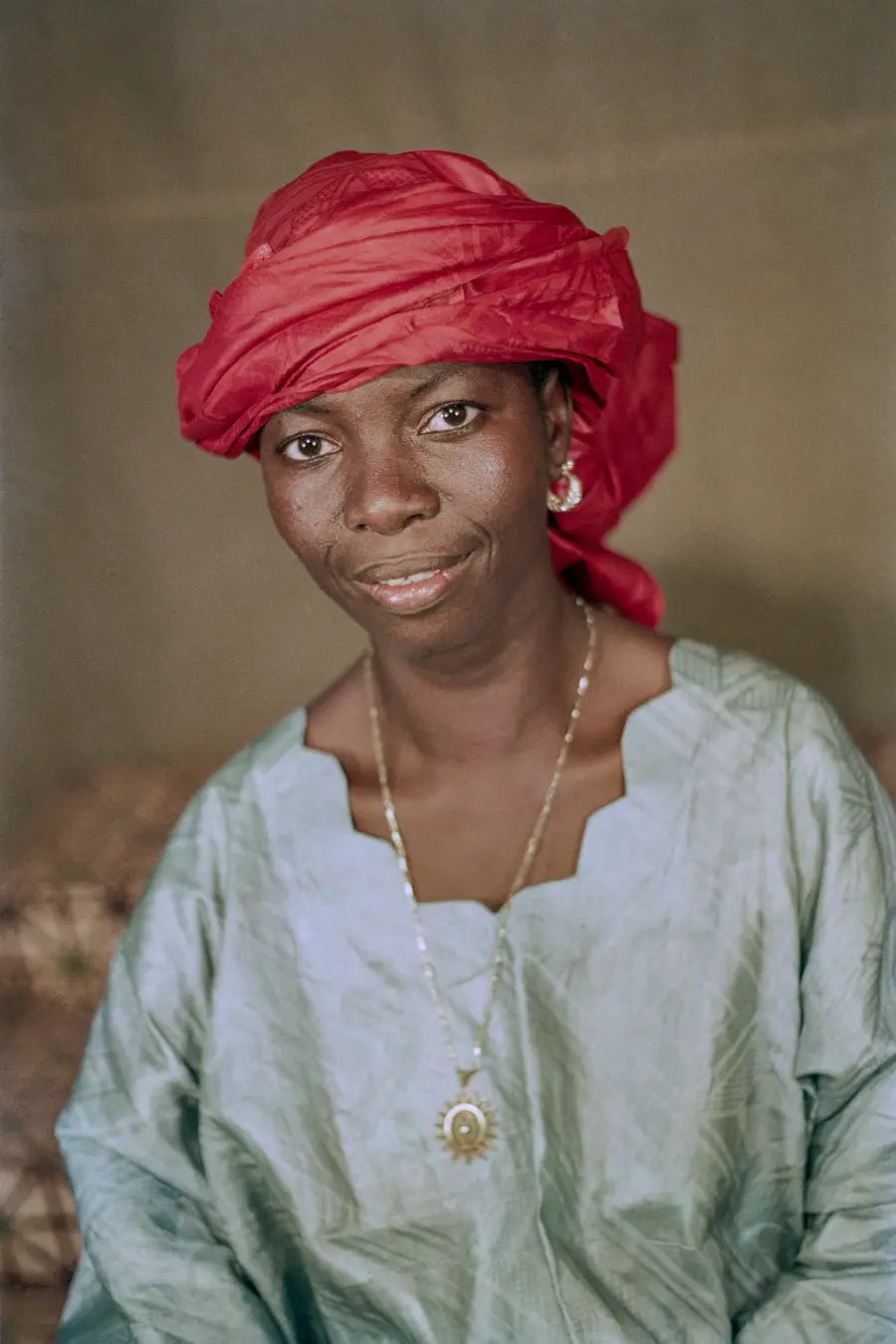 Colour photograph of a woman wearing a red headscarf and a blue abaya-style dress