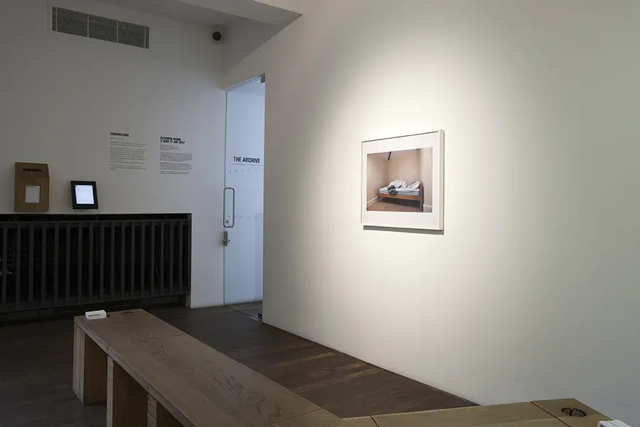 A dog-legged bench in front of a framed colour photograph.