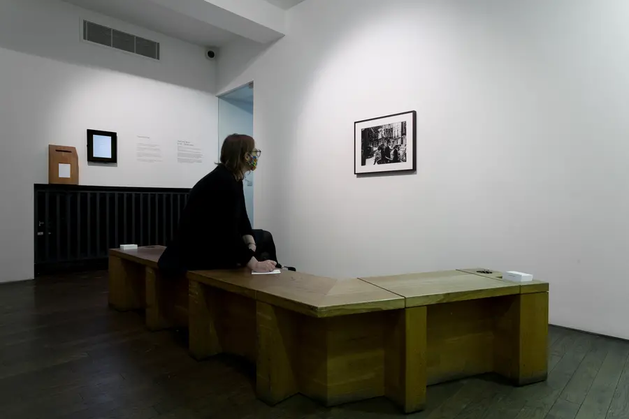 Person on a bench looking at frame black and white photograph. 