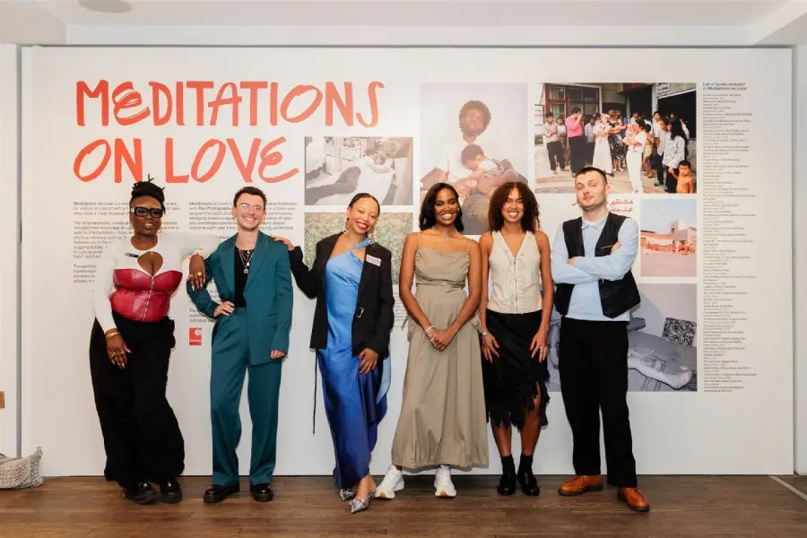 Colour photograph of a group of people standing infront of a gallery wall