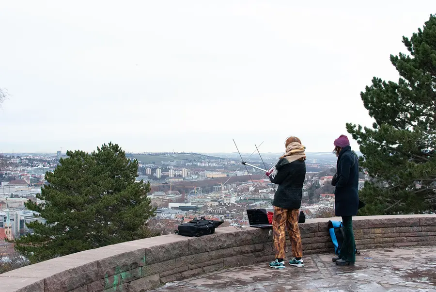 Two people managing an antenna and a laptop outdoors 