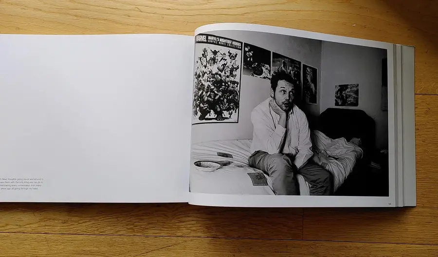 A photograph of a book open on a page of a man sat on a bed.