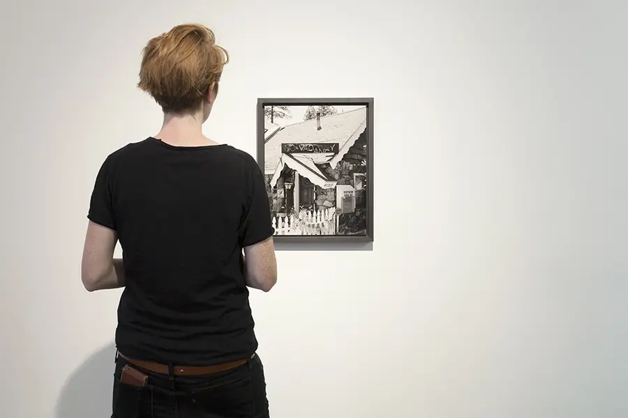 Person looking at a framed black and white photograph of a house hotel.