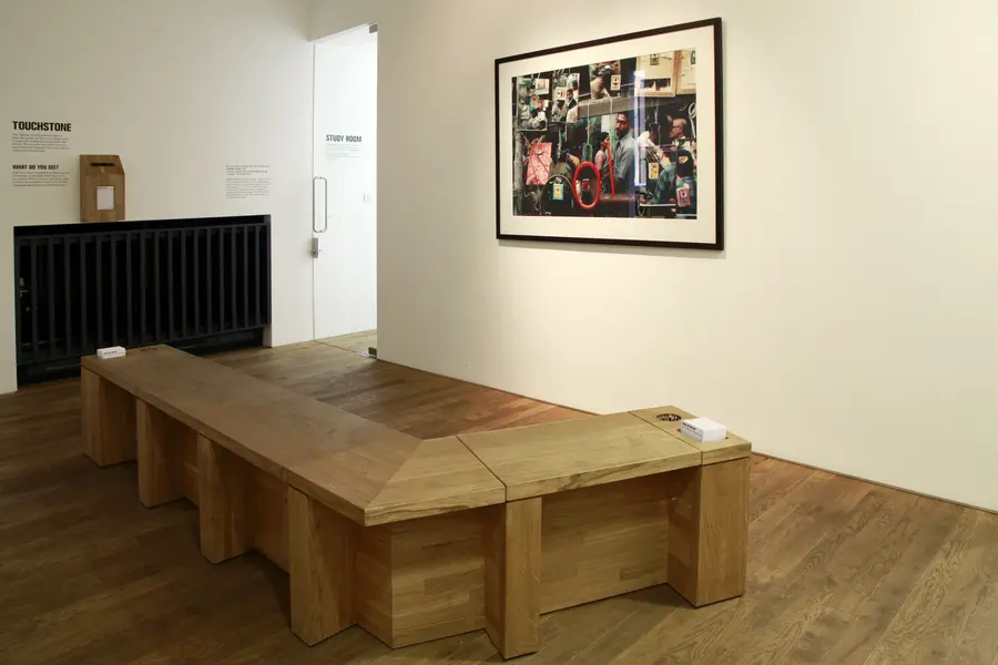 A dog-legged bench is placed in front of a large, framed photograph.