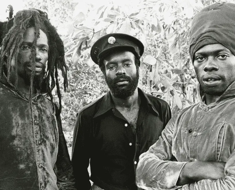 A black and white image of the three members of the reggae group The Abyssinians looking down the camera lens with relaxed expressions.