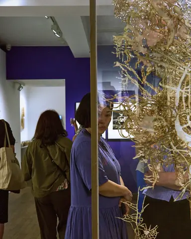 A woman dressed in a purpled dress explores a gallery space