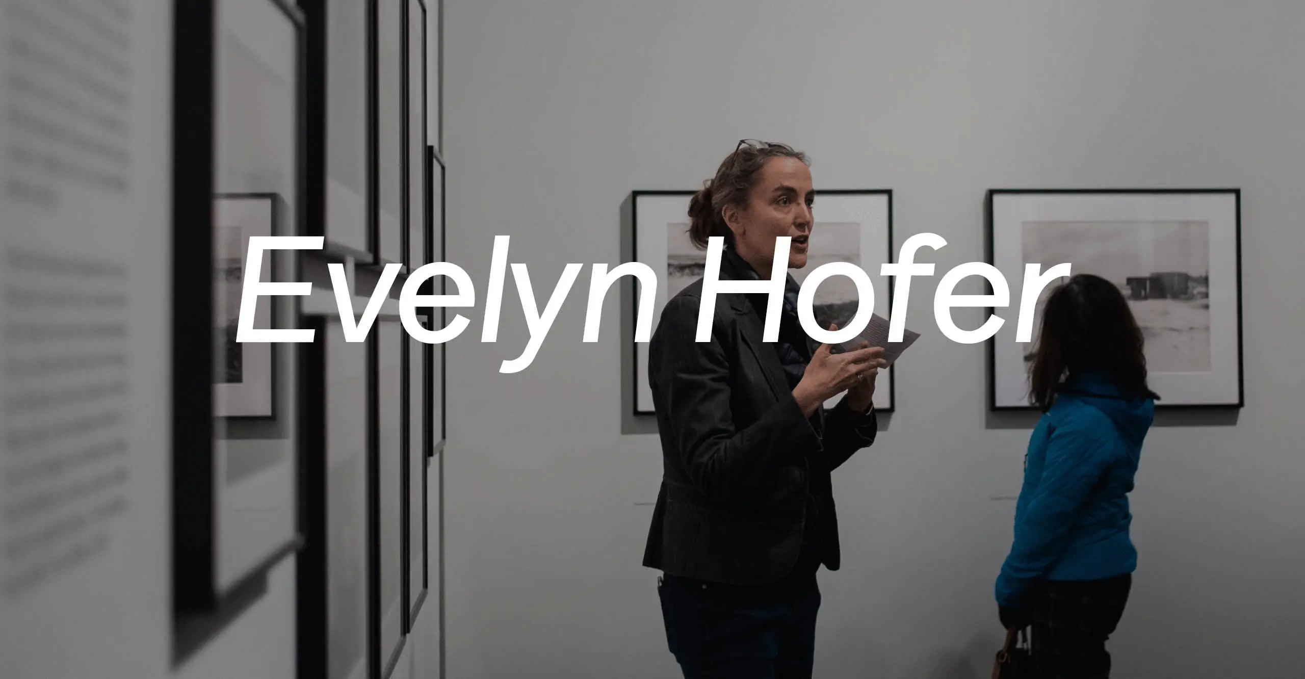 Gif of two images. The first of a blue digital world with the words 'Between Worlds' over it and the other of a person giving an exhibition tour in a Gallery space with the words 'Evelyn Hofer' over it