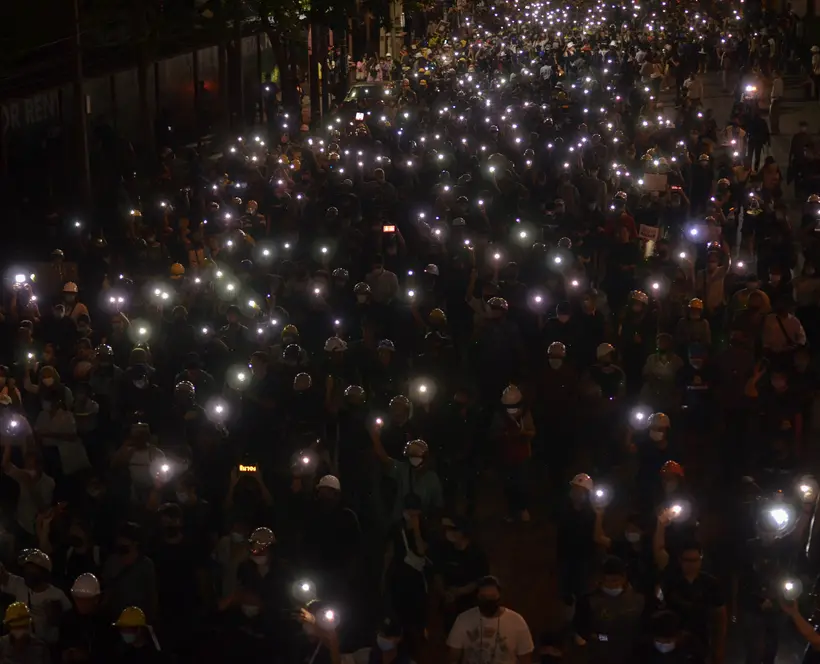 A photograph of a crowd of people holding lights in the night.