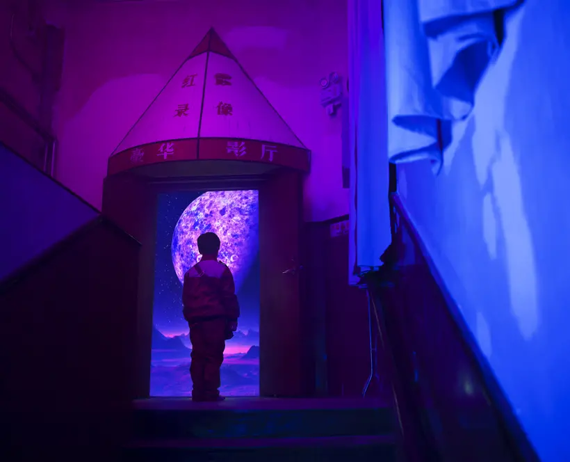Still from Nova that shows a single figure in the centre, just below a doorway. Whole image is aglow in blue and dark purple tint from an unclear light source.