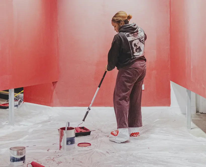 Person painting a wall red. 