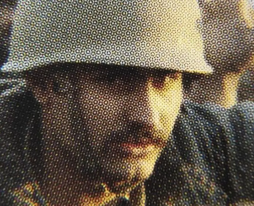 Close up of a person with a moustache wearing an army helmet