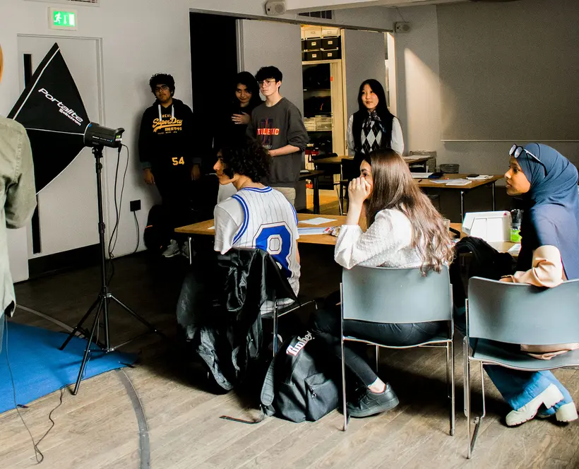 A photograph of a group of students watching a studio lighting demo.