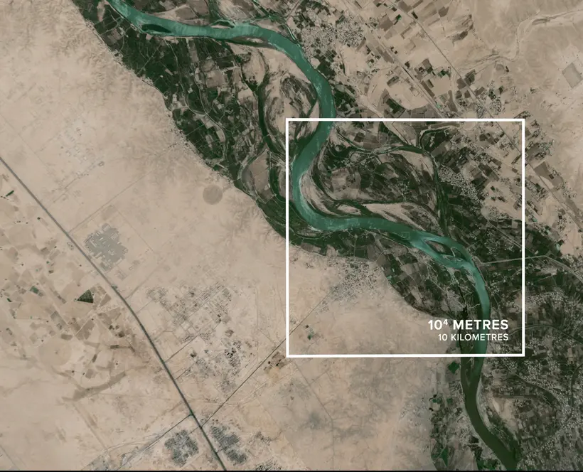 An aerial photograph of a greenish river running through an arid environment, with a superimposed white square on the centre, with text inside reading: 10^4 metres, 10 Kilometres