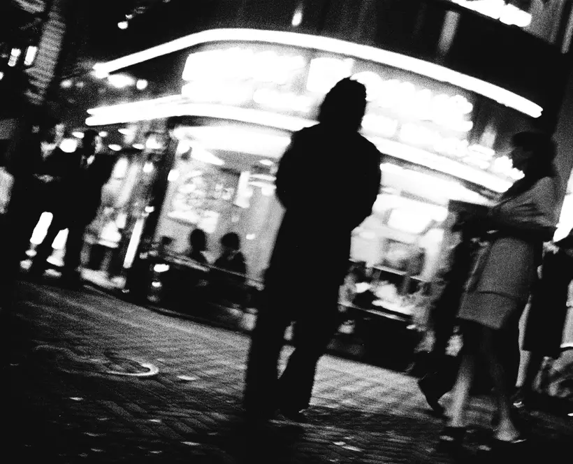 Black and white image of a figure with their back facing in front of a cinema