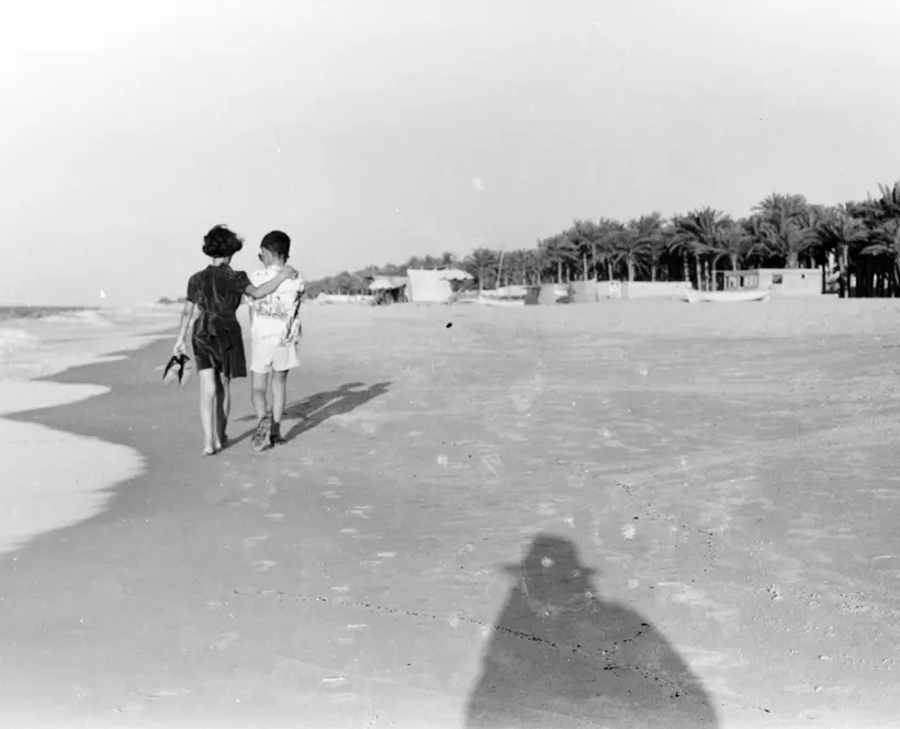 Two figures walking on a beach