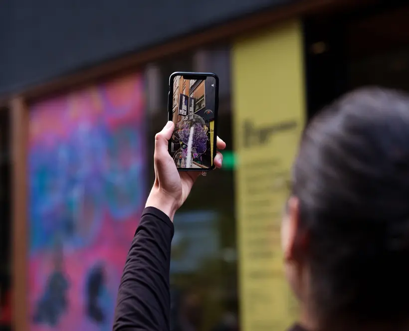 A Photograph of a gallery visitor using a mobile device to view an augmented reality artwork.