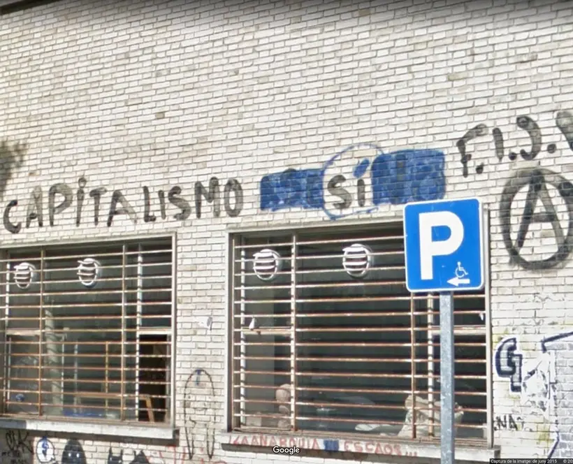 A screenshot of a the façade of a building on Google Street View with 'capitalismo si' graffitied 
