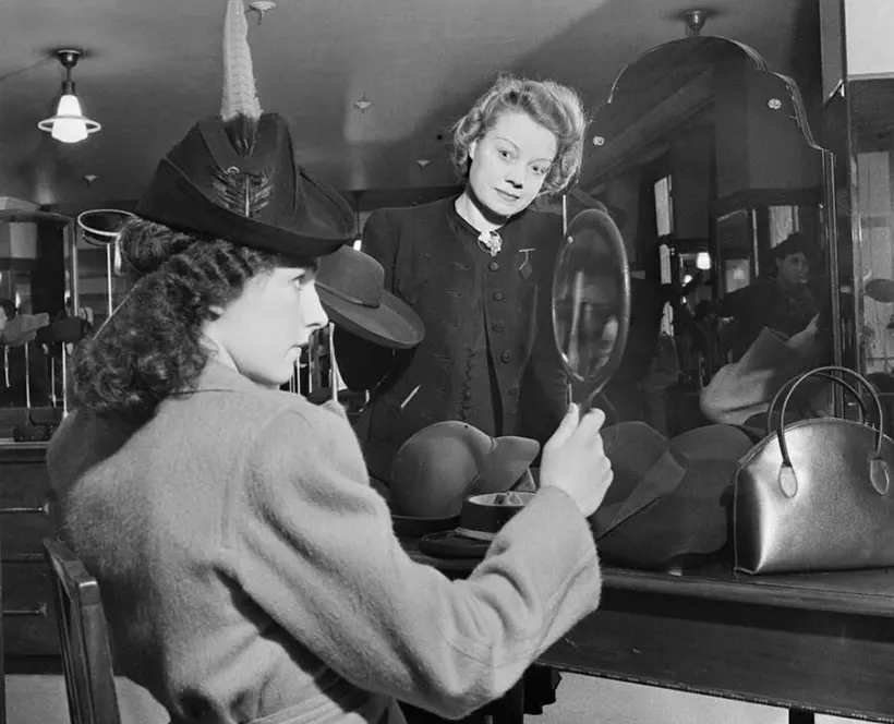 A customer tries on a new hat in the millinery department of Bourne and Hollingsworth on London's Oxford Street in 1942