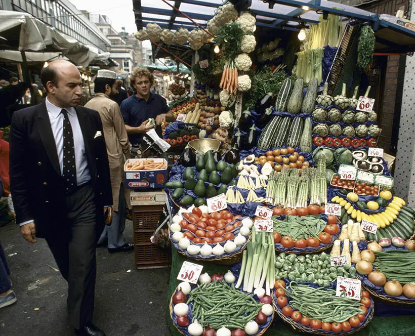 A man walks past a fruit and veg stall at Berwick Street Market
