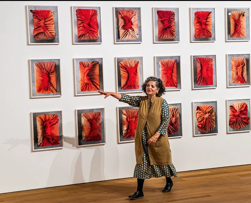 Colour photograph of a person standing in front of a wall of framed images