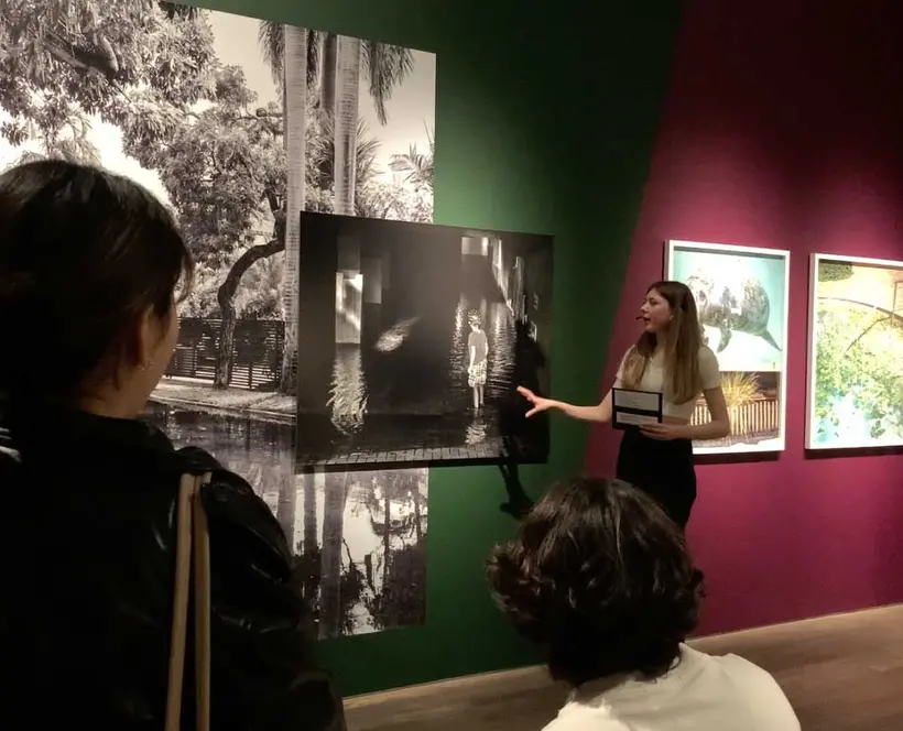 A person stands in the gallery in front of a photograph.