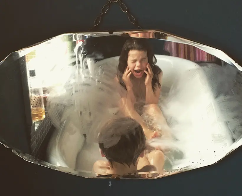 A picture of two children having an argument in a bathtub. One has her fingers in her ears.