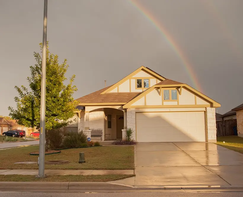 An image of a house bathed in pink light, with a rainbow over it