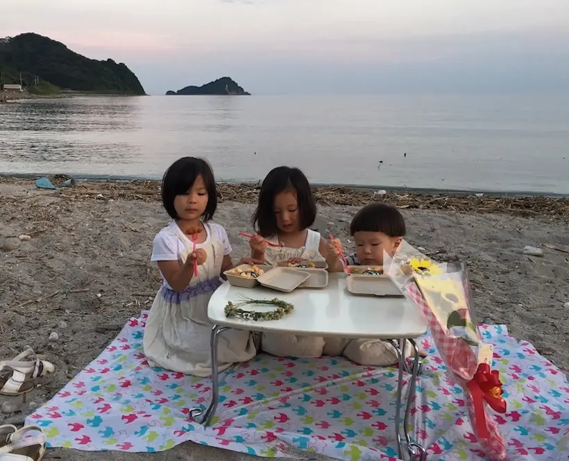 A photograph of the Misa Hamasaki's three children having a picnic on the beach